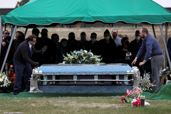 Family members of JBS employee Saul Sanchez watch as his casket is lowered during his funeral after he died of COVID-19 in Greeley, Colorado, last month.