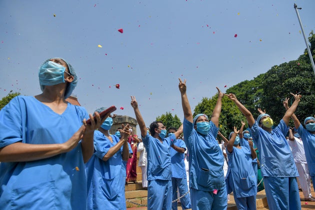 Medical staff cheer as an Indian Air Force (IAF) Mi-17 helicopter drops flower petals over the Victoria...