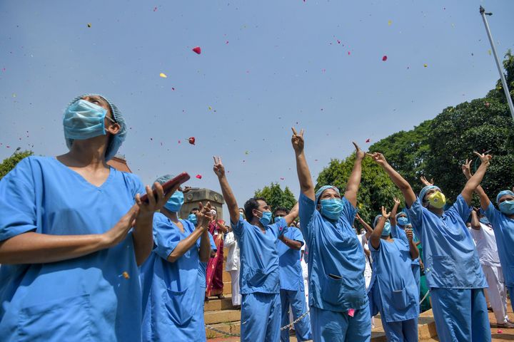 Medical staff cheer as an Indian Air Force (IAF) Mi-17 helicopter drops flower petals over the Victoria Hospital to pay tribute to 'frontline warriors' fighting against the spread of the COVID-19 coronavirus, in Bangalore on May 3, 2020. (Photo by Manjunath Kiran / AFP) (Photo by MANJUNATH KIRAN/AFP via Getty Images)