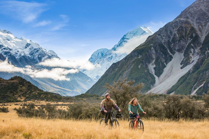 Friends ride mountain bikes through the Mount Cook National Park.