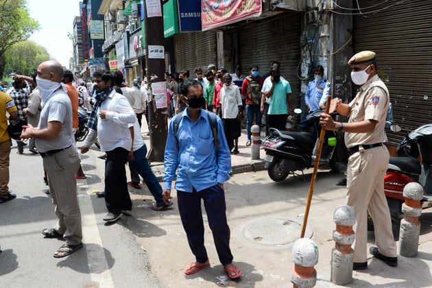 Police disperse people lining up to buy alcohol near a liquor shop in New Delhi on May 4,
