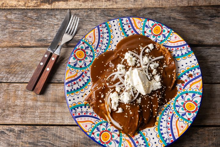Traditional Mexican mole sauce enchiladas with cheese and sesame seeds.