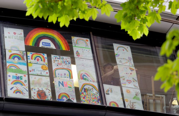 A member of staff puts up rainbow pictures in the window of DLD College