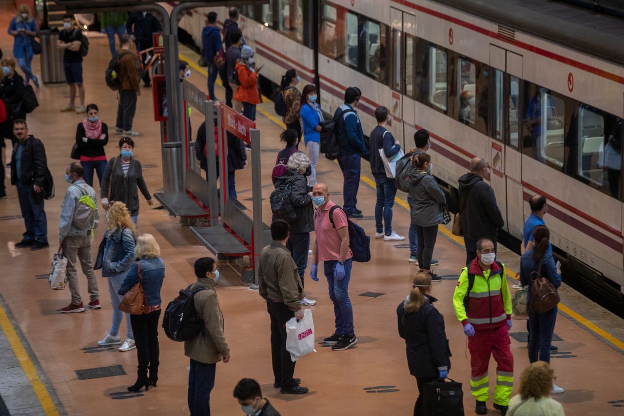 Commuters wearing face masks to protect against coronavirus stand on the platform at Atocha train station in Madrid. 