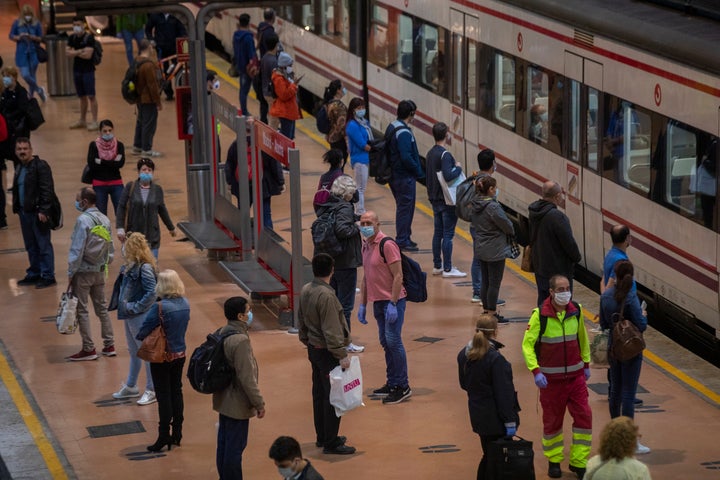 Commuters wearing face masks to protect against coronavirus stand on the platform at Atocha train station in Madrid.&nbsp;