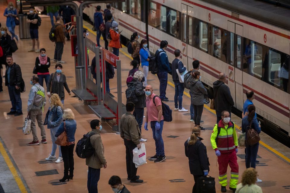 Commuters wearing face masks to protect against coronavirus stand on the platform at Atocha train station in Madrid. 