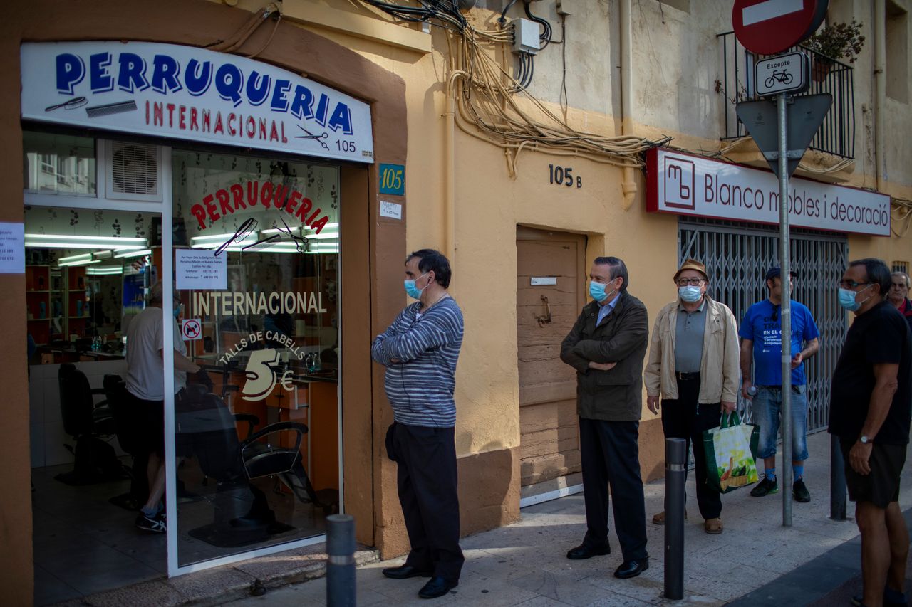 Men line up at a barber's in Barcelona.