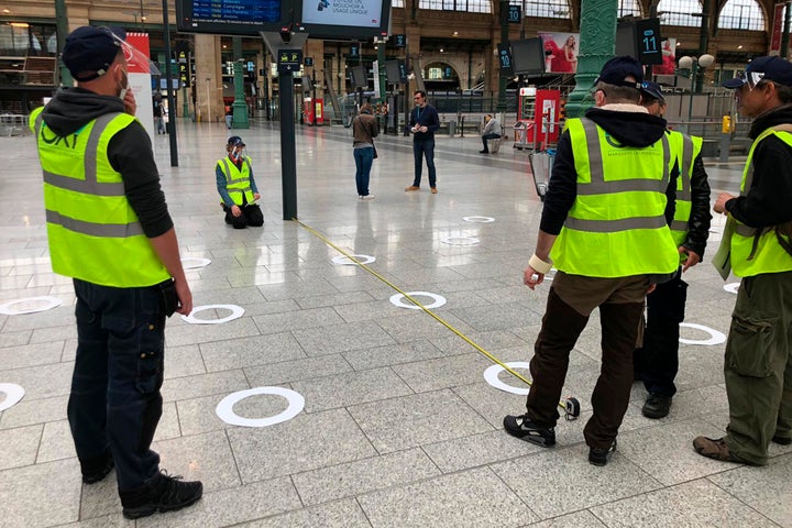 Workers measure the distance between circles to help passengers at Paris' Gare du Nord train station maintain social distanci