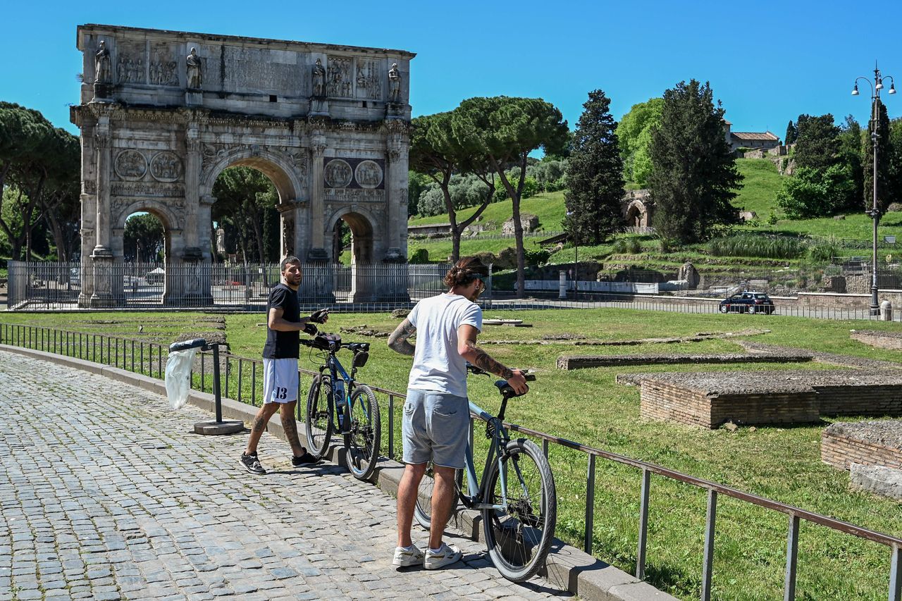 Cyclists park their bikes near the Arch of Constantine monument in central Rome.