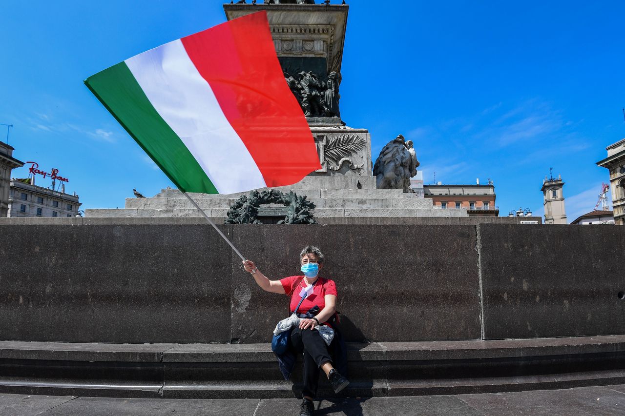 A woman waves the Italian flag in Milan on Monday as Italy starts to ease lockdown measures. 