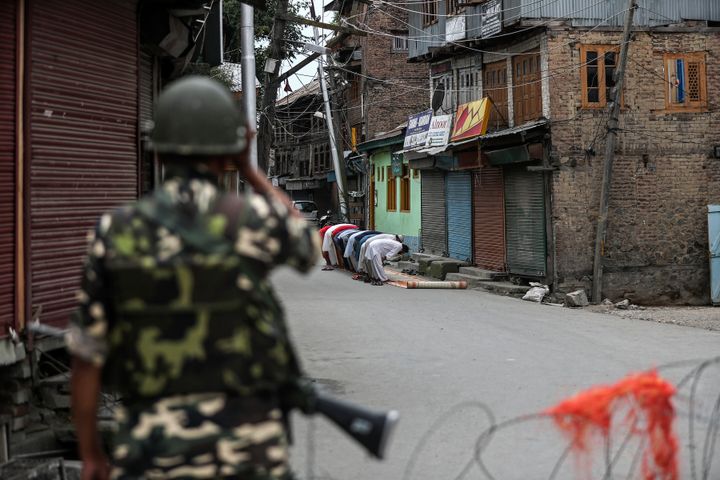 A paramilitary soldier stands guard as Kashmiri Muslims offer Friday prayers on a street outside a local mosque during curfew like restrictions in Srinagar, India, Aug. 16, 2019. The image was part of a series of photographs by Associated Press photographers which won the 2020 Pulitzer Prize for Feature Photography. (AP Photo/Mukhtar Khan)