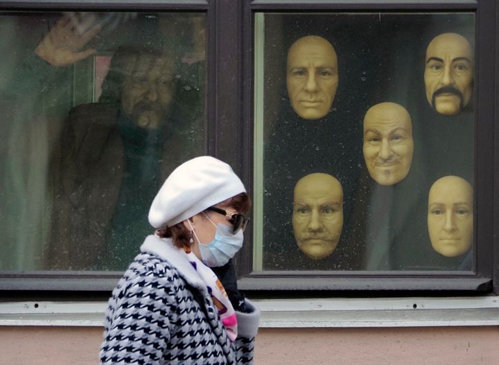Μι γυναίκα με μάσκα περνά μπροστά από βιτρίνα με κέρινα πρόσωπα, στην Αγ.Πετρούπολη της Ρωσίας (4 Μαΐου) 
