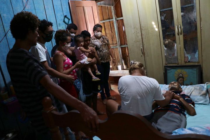 Συγγενείς γύρω από έναν νεκρό 88χρονο που κατέληξε στο σπίτι του στο Μανάου της Βραζιλίας. Ο ηλικιωμένος πέθανε μετά από βαριά πνευμονία, δεν εξετάστηκε για τον ιό και οι δικοί του καταγγέλλουν πως περίμεναν 10 ώρες για να παραλάβει το γραφείο κηδειών το άψυχο κορμί του (30 Απριλίου)