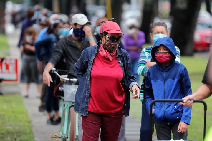 People line up for food at a food distribution point for people economically impacted by the coronavirus pandemic, organized by New Orleans City Councilman Jay Banks, in New Orleans, Wednesday, April 29, 2020. (AP Photo/Gerald Herbert)