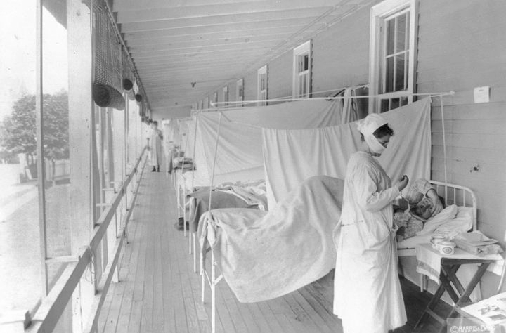 In this November 1918 photo made available by the Library of Congress, a nurse takes the pulse of a patient in the influenza ward of the Walter Reed hospital in Washington. (Harris & Ewing/Library of Congress via AP)
