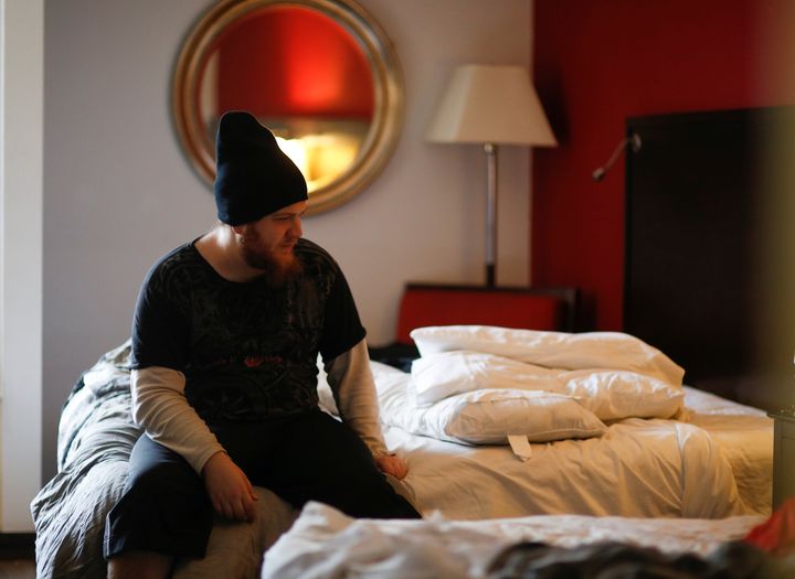 Travis Johnson sits on his bed in his room at the Red Lion Hotel, one of Downtown Emergency Service Center's temporary shelter locations during the coronavirus outbreak.