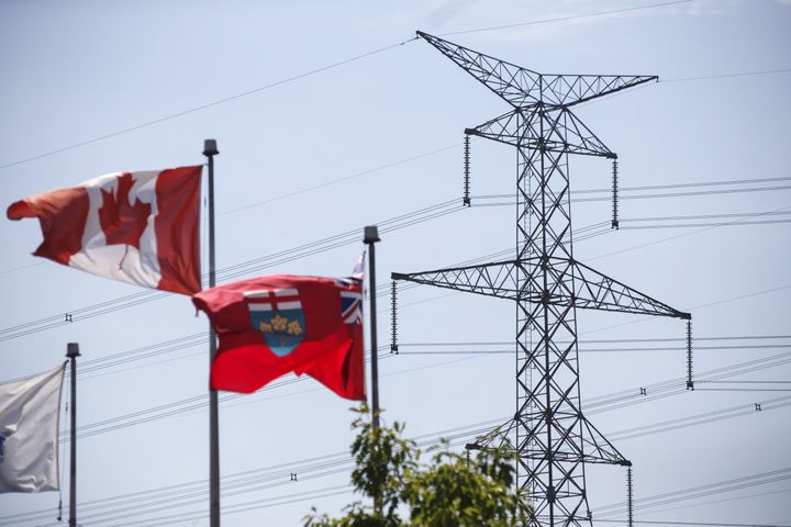 The flags of Canada and Ontario fly in front of a Hydro One transmission tower in Toronto on July 12, 2018.