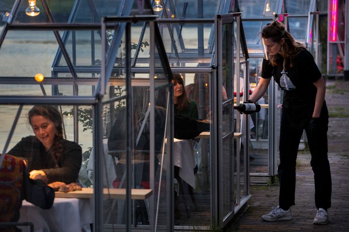Staff at the Mediamatic restaurant serve food to volunteers seated in small glasshouses during a try-out of a setup which respects social distancing abiding by government directives to combat the spread of the COVID-19 coronavirus in Amsterdam, Netherlands, Tuesday, May 5, 2020. (AP Photo/Peter Dejong)