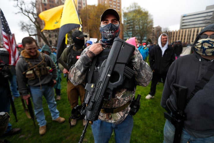 A protester carries his rifle at the State Capitol in Lansing, Mich., Thursday, April 30, 2020. (AP Photo/Paul Sancya)