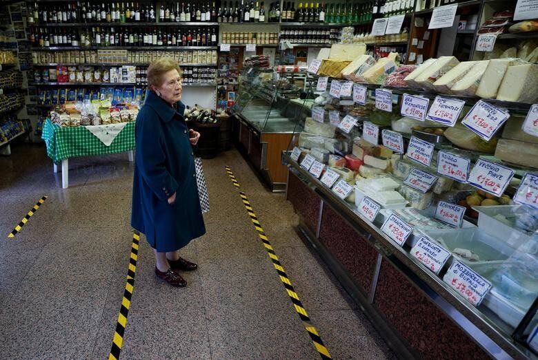 Ρώμη, Ιταλία: Ηλικιωμένη προσπαθεί να συνηθίσει τις διαχωριστικές γραμμές στα καταστήματα, περιμένοντας να εξυπηρετηθεί.