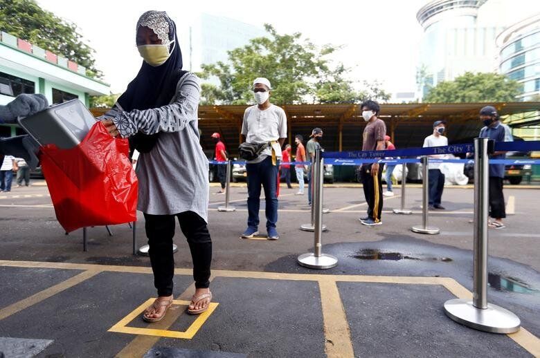 Τζακάρτα, Ινδονησία: Ανθρωποι παραλαμβάνουν ρύζι από... ATM, κρατώντας πάντα αποστάσεις μεταξύ τους.