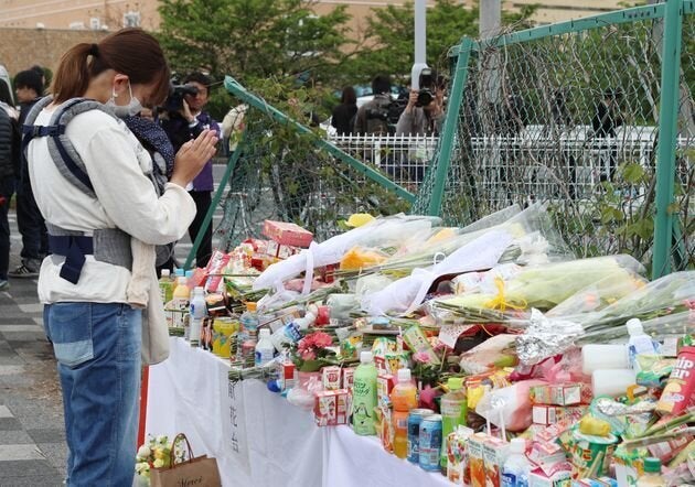 保育園児らの列に車が突っ込んだ事故現場で手を合わせる女性＝5月9日午前、大津市