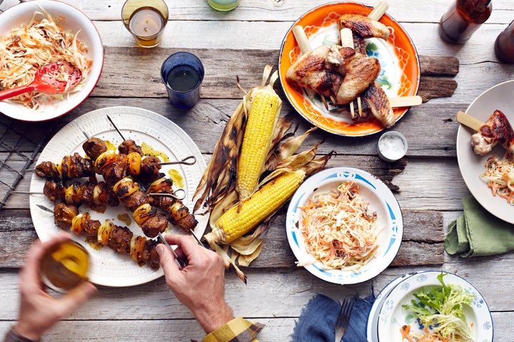 Mans hand picking up lamb and chicken skewer from table