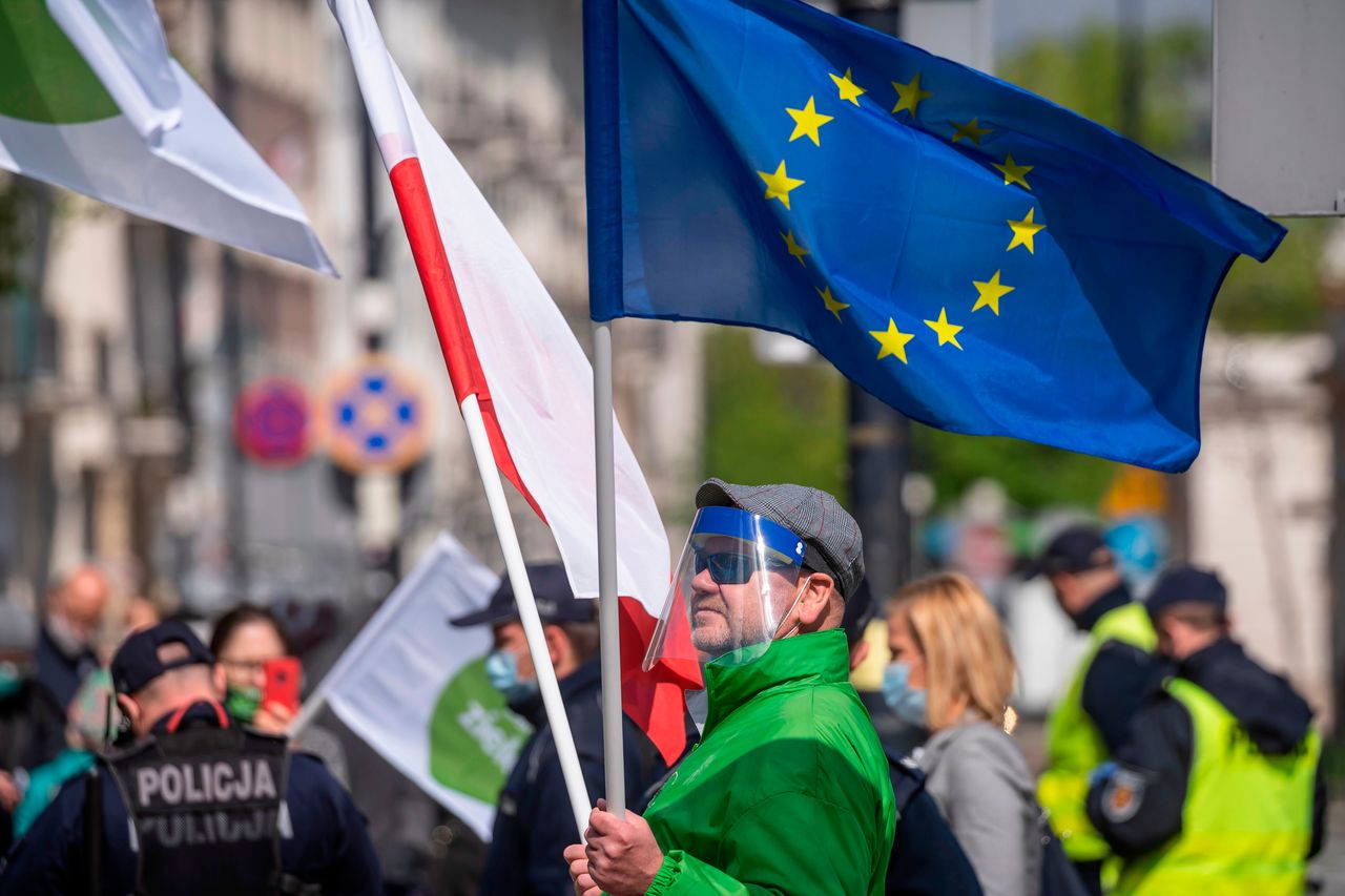 A man holds a Polish and an European flag during a demonstration outside parliament, on May 7, 2020 in Warsaw.