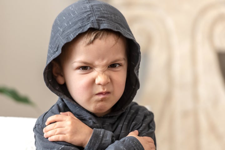 very upset three years old boy looking at the camera wearing a hoodie