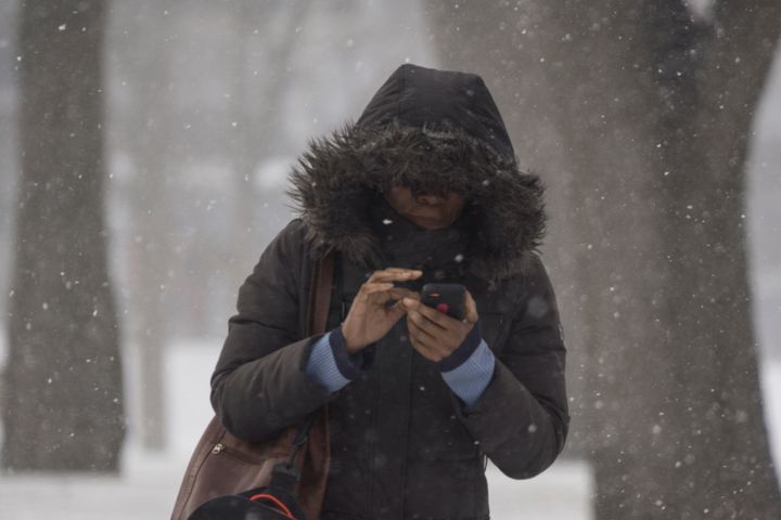 A woman checks her phone while walking in light snow in Toronto in January 2015. Parts of Ontario and Quebec are expected to see winter-like weather conditions during the Mother's Day weekend.