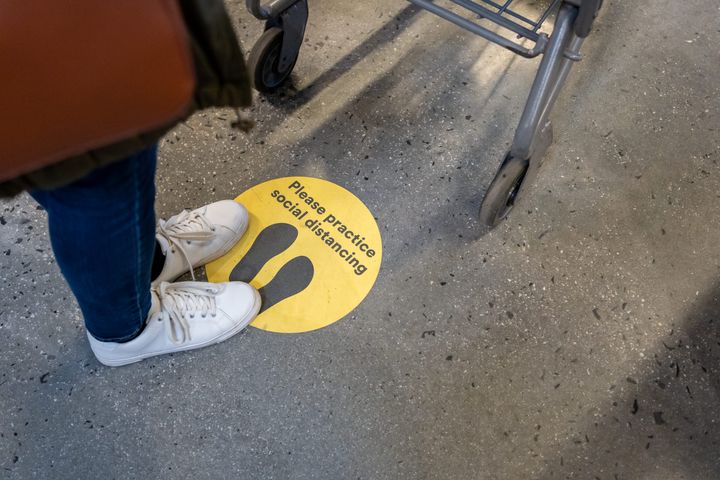 A sign on the floor of a supermarket reminding shoppers to stay apart