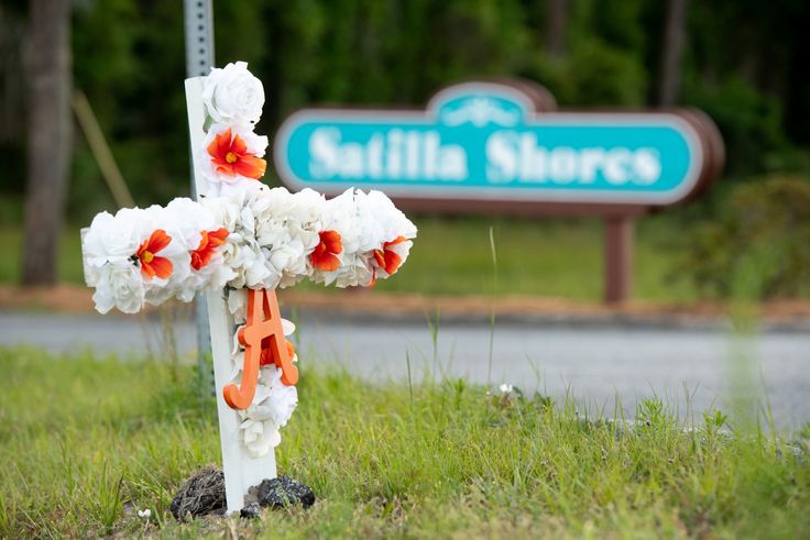 A cross with flowers and a letter "A" sits at the entrance to the Satilla Shores neighborhood where Ahmaud Arbery was shot and killed on May 6 in Brunswick, Georgia.