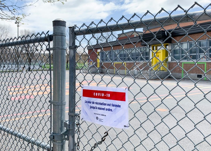 A COVID-19 sign is shown on a gate at a school in Montreal on May 5, 2020.