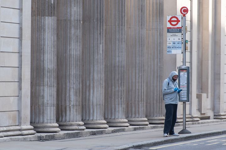 A man waits for a bus outside the Bank of England, London, as the UK continues in lockdown to help curb the spread of the coronavirus.