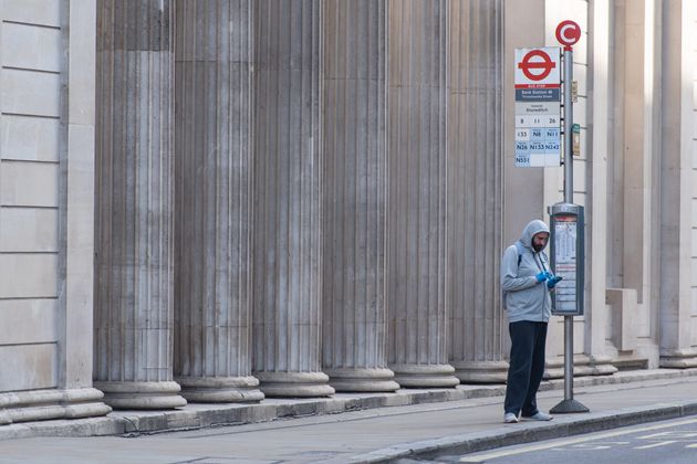 A man waits for a bus outside the Bank of England, London, as the UK continues in lockdown to help curb the spread of the coronavirus.