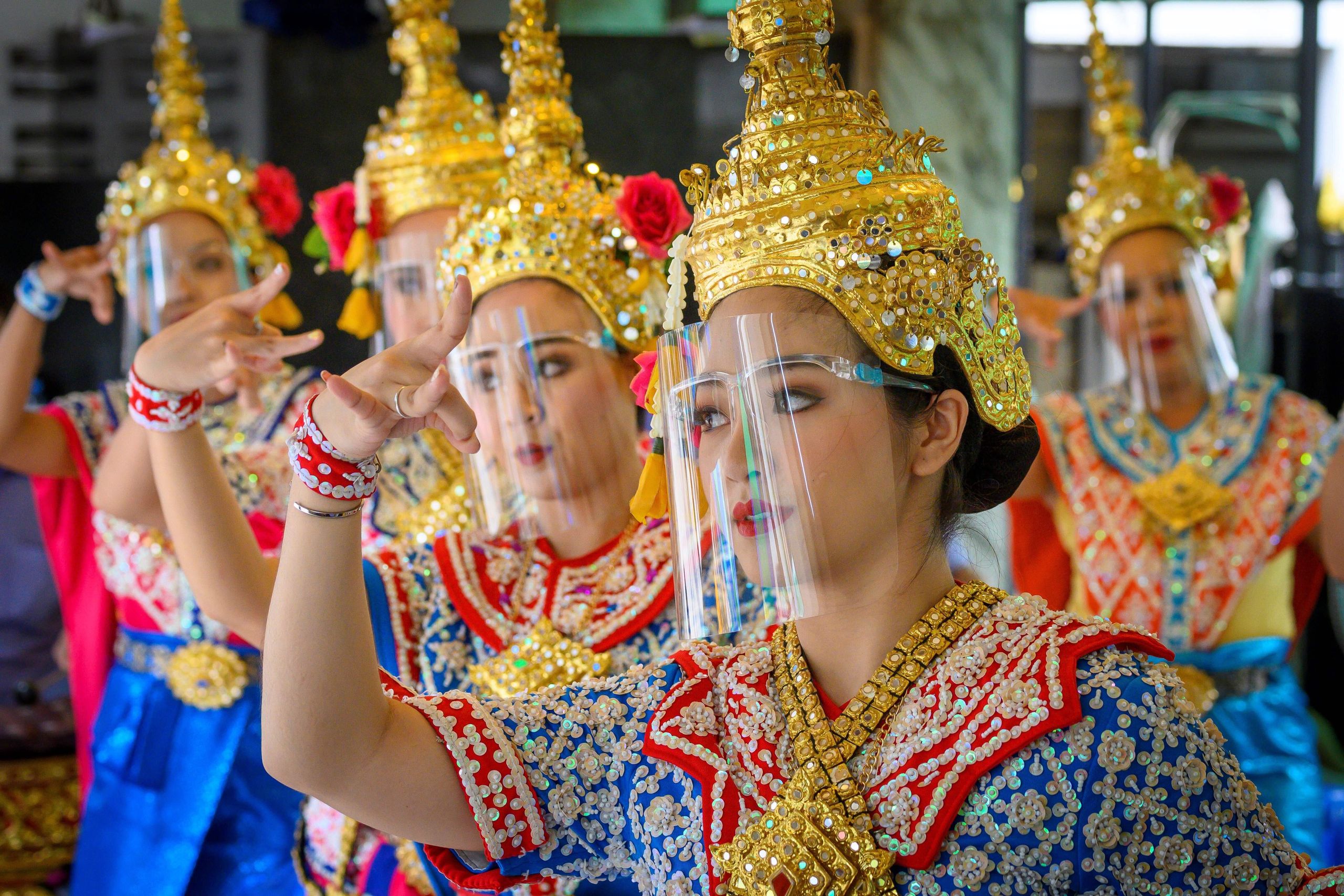 Traditional Thai dancers wearing protective face shields perform at the Erawan Shrine, which was reopened after the Thai government relaxed measures to combat the spread of the novel coronavirus in Bangkok on Monday.