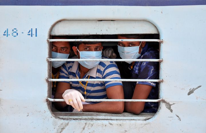 Migrant workers, who were stranded in the western state of Rajasthan due to a lockdown imposed by the government to prevent the spread of coronavirus disease (COVID-19), wear protective masks as they look out from a window of a train upon their arrival in their home state of eastern West Bengal, at a railway station on the outskirts of Kolkata, India, May 5, 2020. REUTERS/Rupak De Chowdhuri TPX IMAGES OF THE DAY