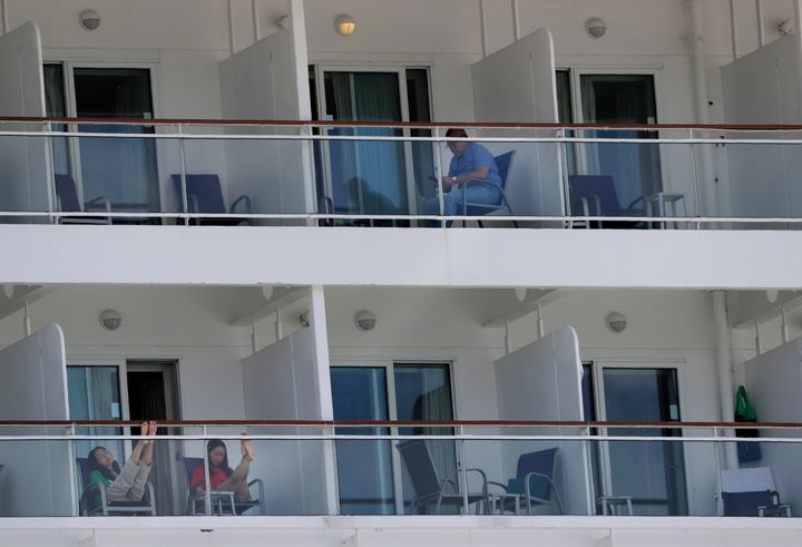 In this May 8, 2020 photo, people aboard the Norwegian Epic cruise ship docked at PortMiami in Miami, sit on their balconies. Tens of thousands of crew members, including U.S. citizens, remain confined to cabins aboard cruise ships, weeks after governments and companies negotiated disembarkation for passengers in the midst of the coronavirus pandemic. Most crew members are stuck in ships with no confirmed cases but are rejected by governments because of new rules to avoid importing more virus cases.