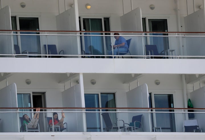 In this May 8, 2020 photo, people aboard the Norwegian Epic cruise ship docked at PortMiami in Miami, sit on their balconies.