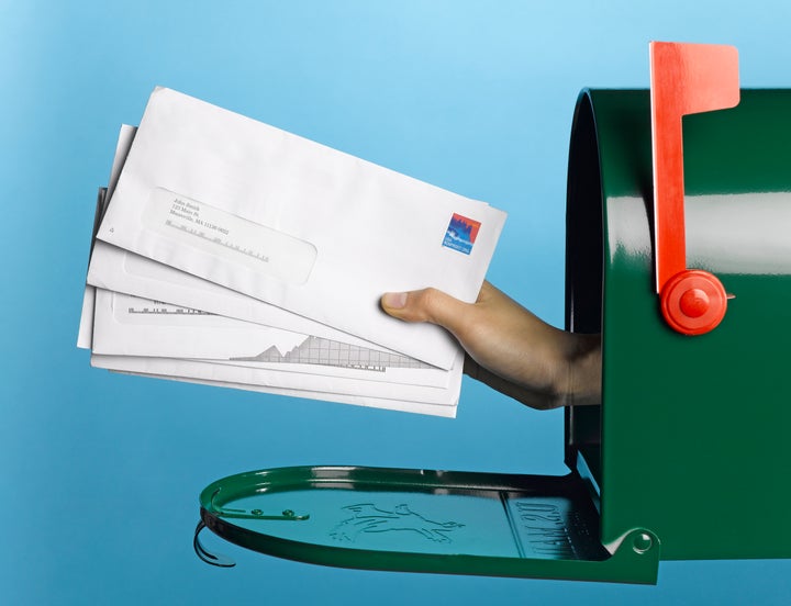 Young woman holding mail out of mailbox, side view