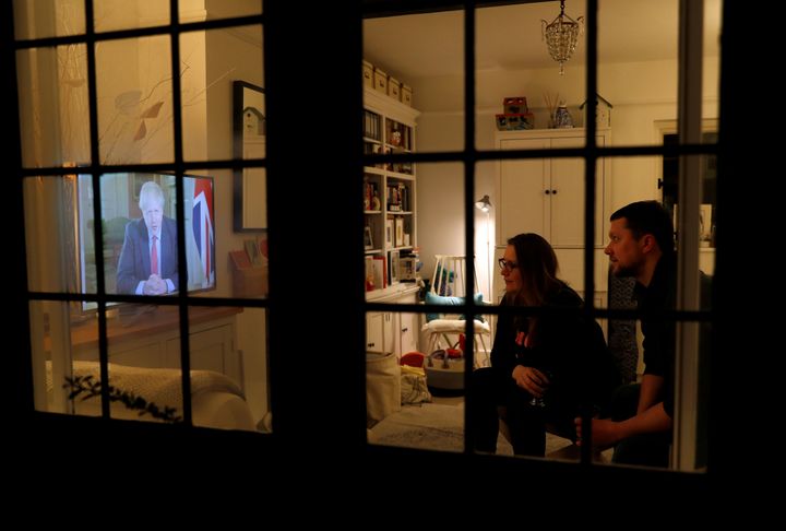 Ενα ζευγάρι Βρετανών μπροστά στην τηλεοπτική οθόνη, σε προηγούμενο τηλεπτοπτικό μήνυμα του πρωθυπουργού Μπόρις Τζόνσον για τον κορονοϊό, στις 23 Μαρτίου 2020. REUTERS/Peter Nicholls