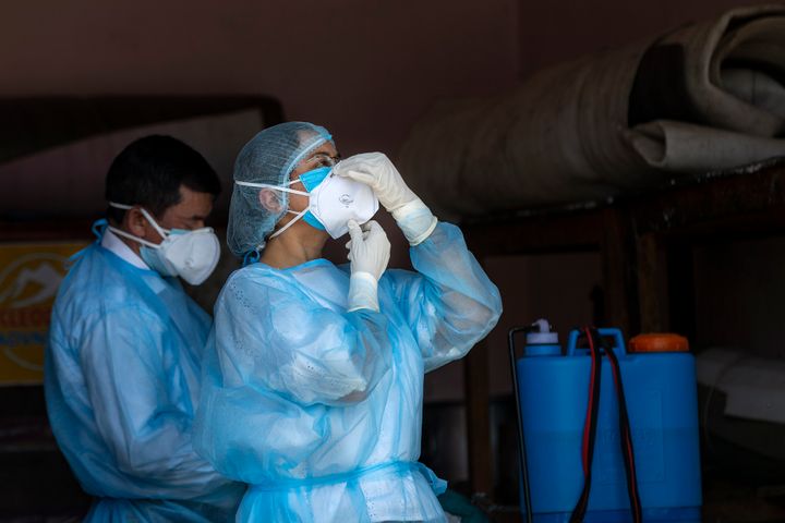 A doctor wears her protective mask before collecting samples from people to be tested for the coronavirus in Dharmsala, May 9, 2020.
