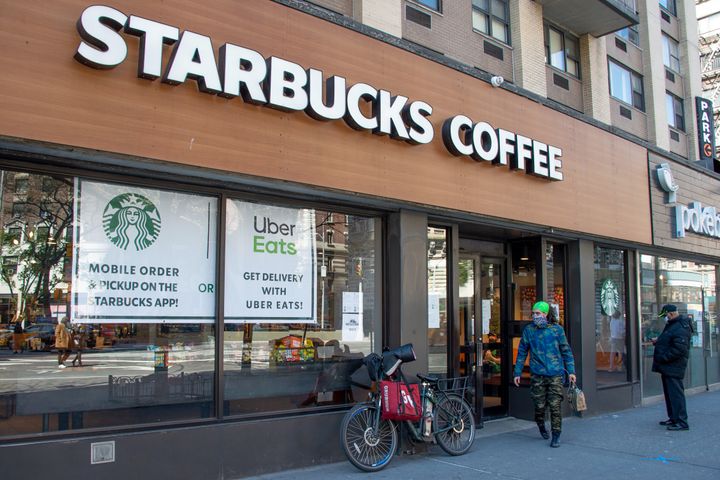 A delivery rider wearing a protective mask picks up an order from Starbucks on April 28 in New York City. Workers across the country are expected to head back to the stores as states reopen.