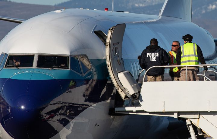 Agents working for U.S. Immigration and Customs Enforcement prepare to board detainees onto a flight in February.