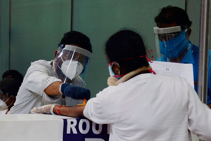 Health officials stamp a quarantine seal on the arm of an citizen evacuated from Dubai by an Air India flight, as she arrived along with others at the Anna International Airport in Chennai on May 9, 2020.