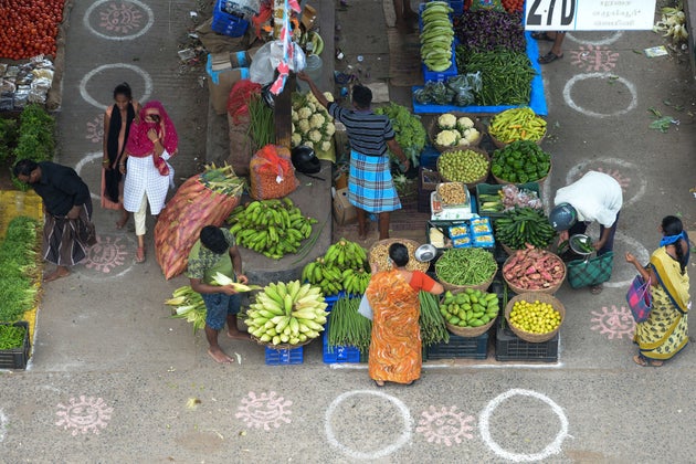 People buy groceries at a temporary market, marked with circles on the floor to maintain social distancing,...