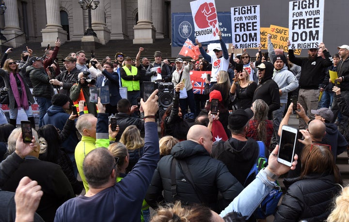 Anti-lockdown protesters chant on the steps of Victoria's state parliament in Melbourne on May 10, 2020 before police arrested 10 protesters - Hundreds of people gathered to protest the state's tough lockdown laws as well as 5G, vaccinations and coronavirus being a hoax.