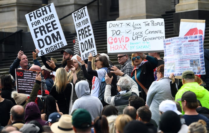 Anti-lockdown protesters hold placards on the steps of Victoria's state parliament in Melbourne on May 10, 2020 before police arrested 10 protesters - Hundreds of people gathered to protest the state's tough lockdown laws as well as 5G, vaccinations and coronavirus being a hoax. 