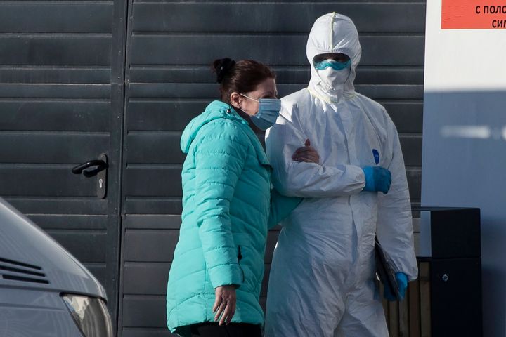 Νοσηλευτής συνοδεύει στο ασθενοφόρο γυναίκα που παρουσιάζει συμπτώματα κορονοϊού, προκειμένου να διακομιστεί σε νοσοκομείο λίγο πιο έξω από τη Μόσχα. 