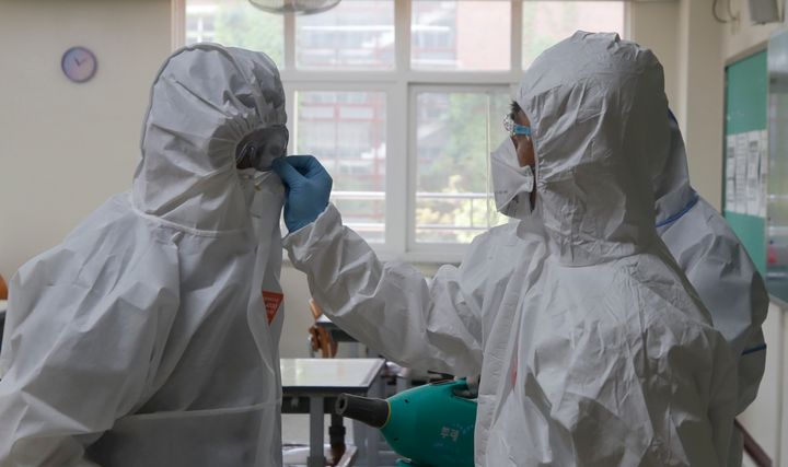 Health officials wearing protective gear check their goggles after spraying disinfectant in Seoul, South Korea, May 11, 2020.